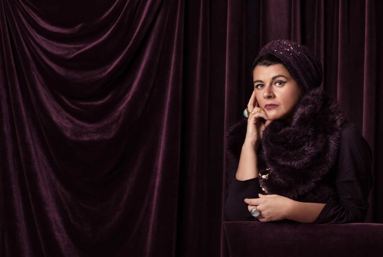 Portrait of Asil Attar against extended plum velvet drapery